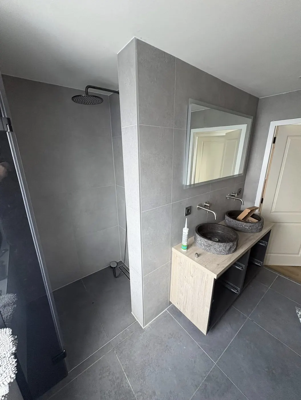 Badkamer in Wijchen met inloopdouche achter een tegelwand en een dubbele wastafel met opzetkommen