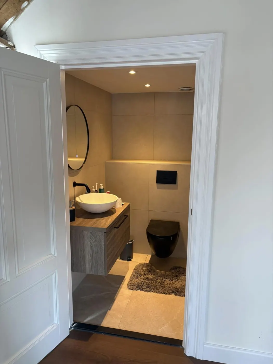 Gerenoveerd toilet in Wijchen met zwart hangtoilet, wastafelmeubel en verlichte richel boven het inbouwreservoir